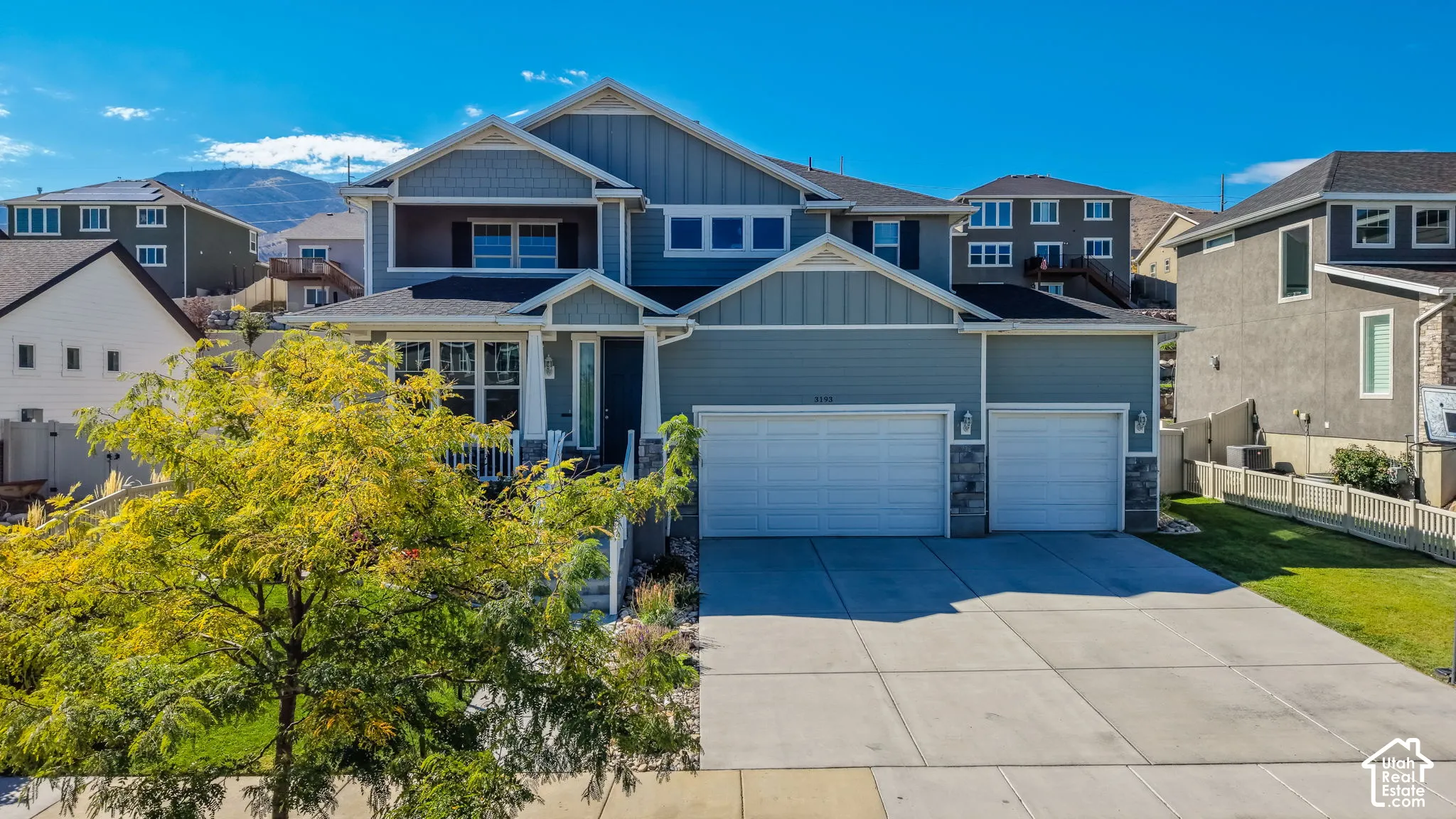 Two-story residence featuring horizontal and vertical siding, stone veneer accents, a covered front entryway, and a three-car garage