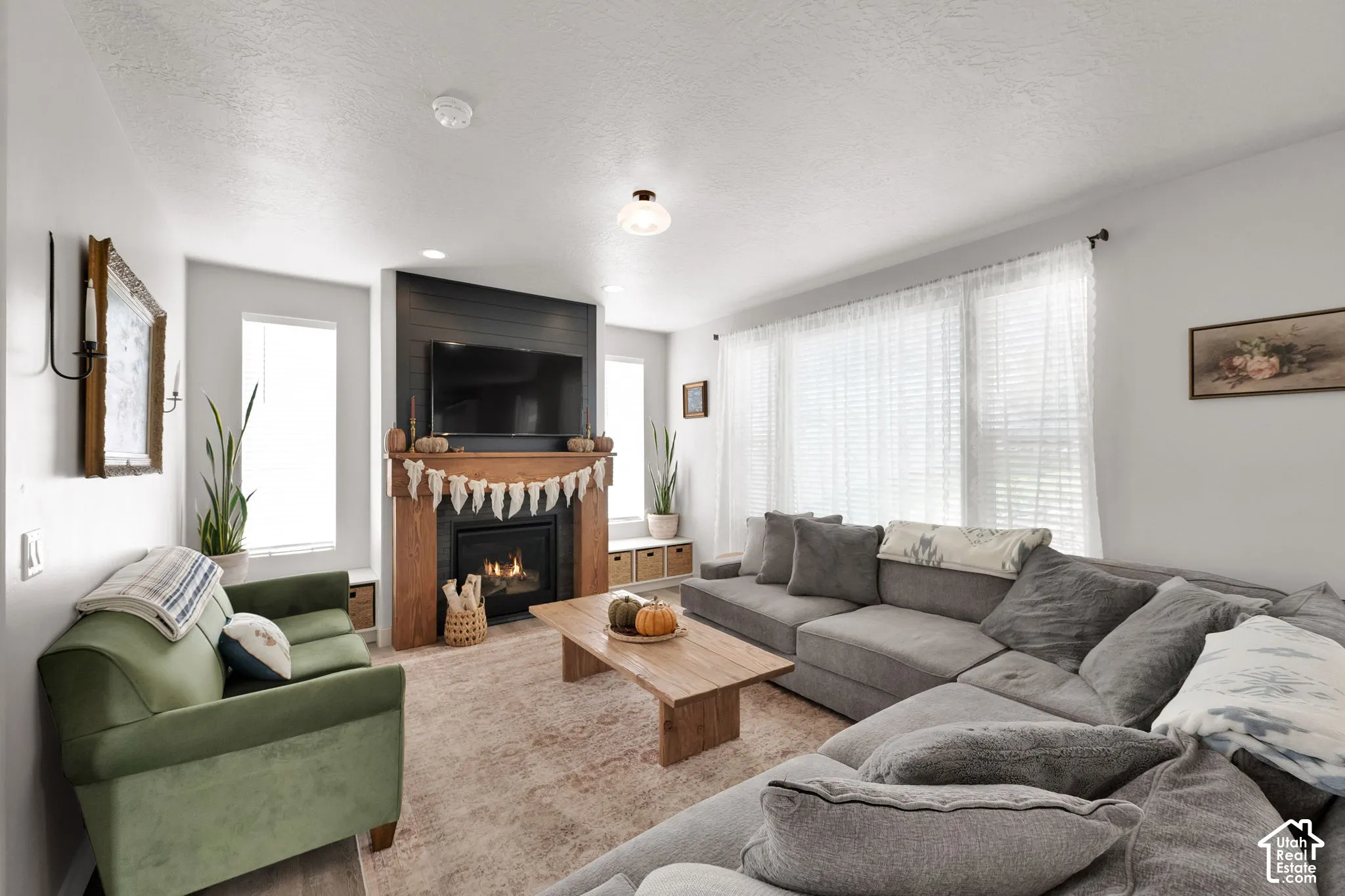 Living area featuring a floor-to-ceiling fireplace with wood mantle and dark wood-plank accent wall, built-in lower cabinetry, and large multi-panel windows