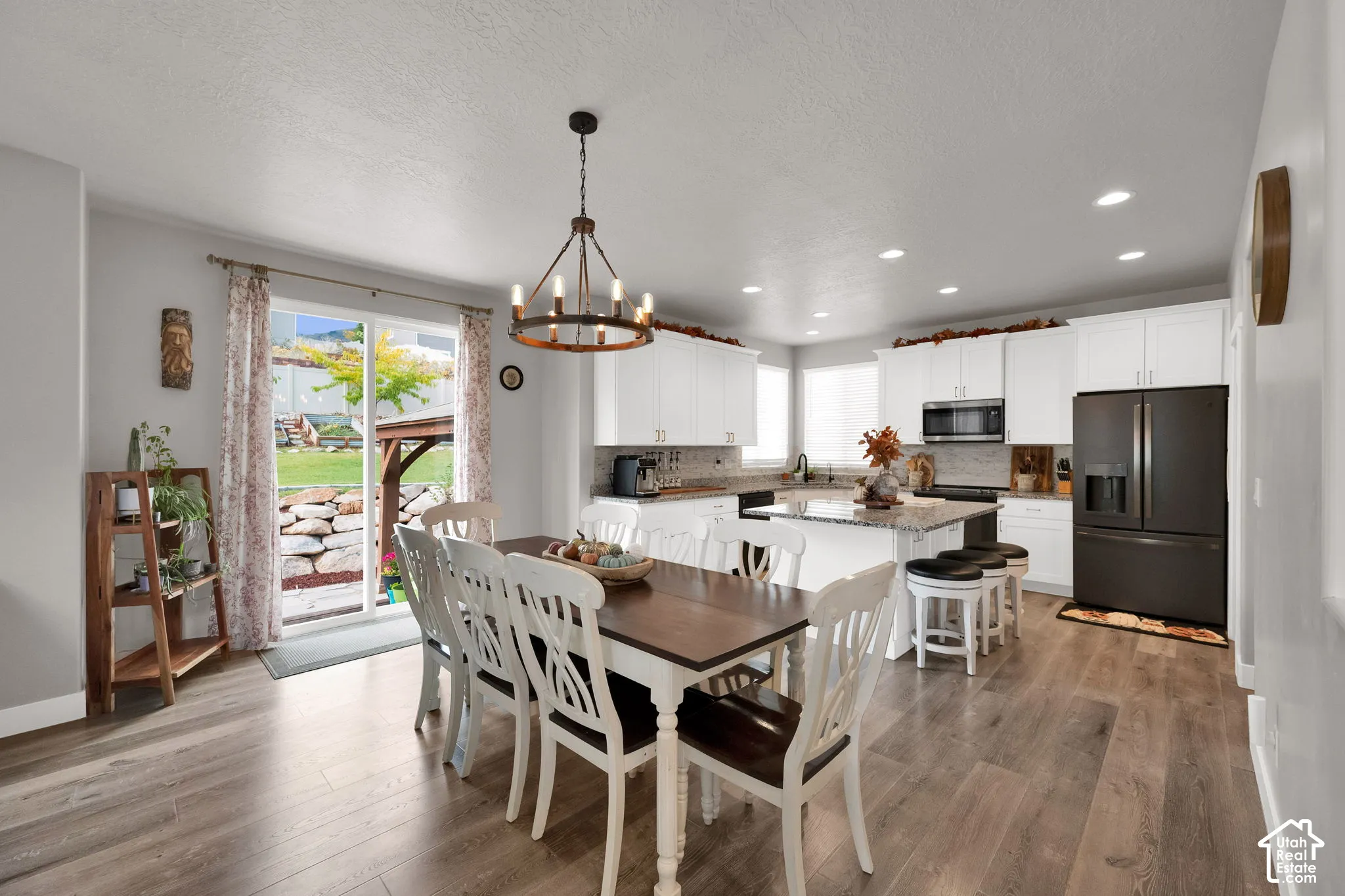 Kitchen featuring white shaker-style cabinetry, center island with stone countertop, stainless steel appliances, recessed lighting, and wood-finish flooring