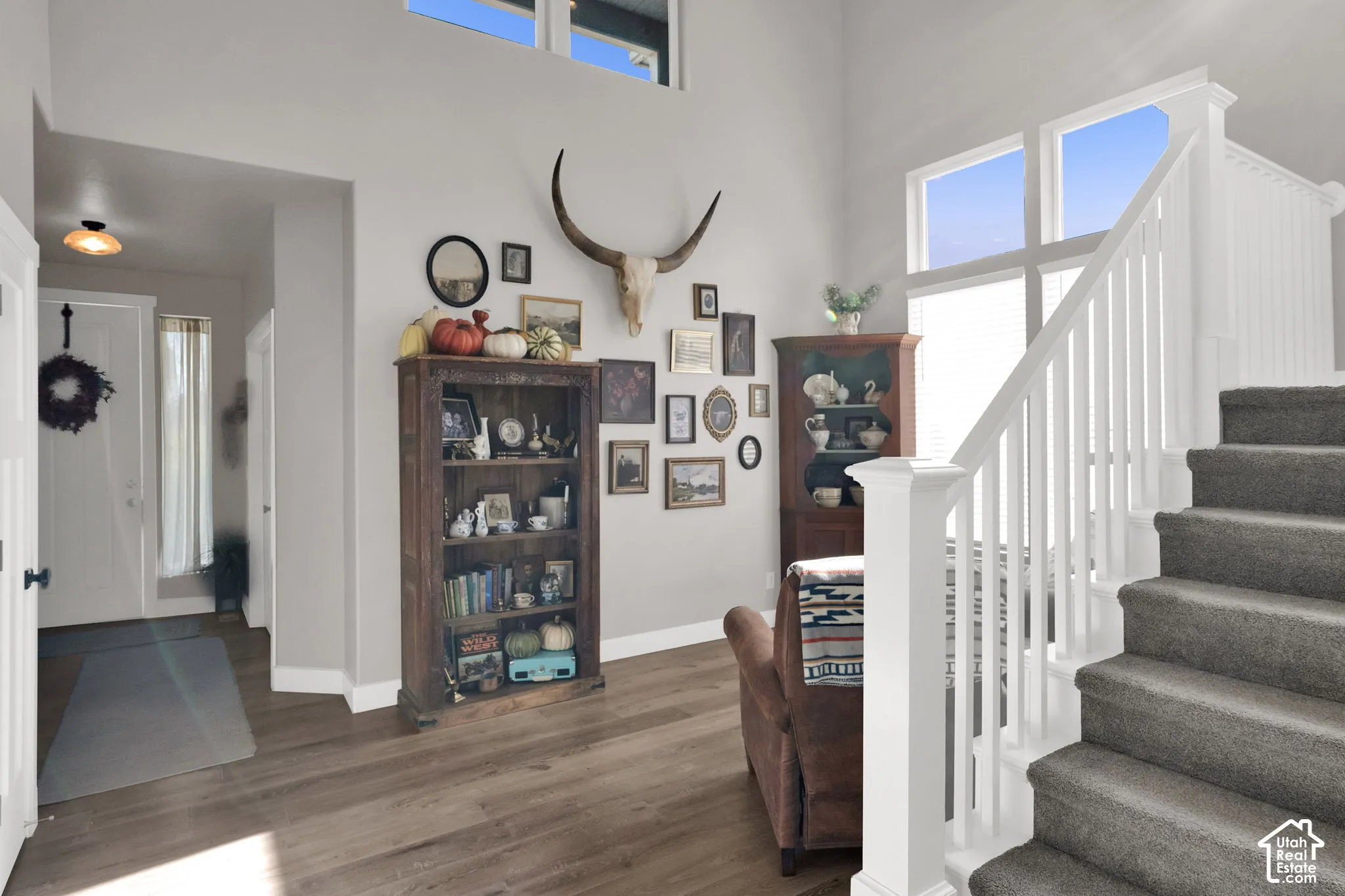 Entryway featuring high vaulted ceilings, expansive multi-pane windows, wood-finish flooring, and a staircase with a white balustrade