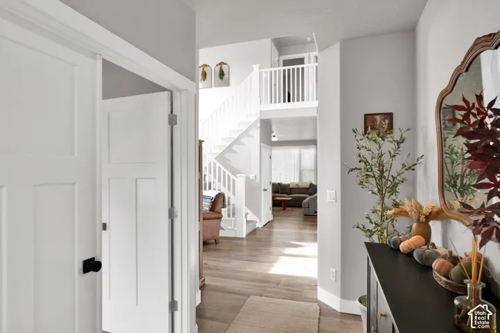 Foyer featuring wood-finish flooring, a white staircase with a wooden handrail and balusters, and multi-panel doors with matte black hardware