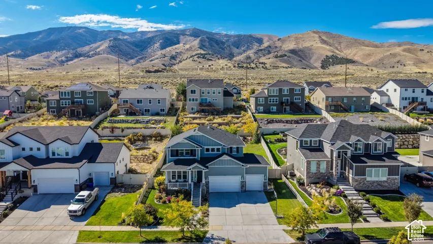 Multi-level residential community featuring concrete driveways, attached multi-car garages, exterior stone accents, and expansive mountain terrain backdrop