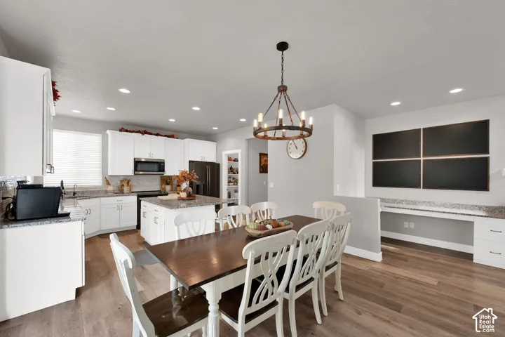 Kitchen featuring white cabinetry, stone countertops, central island, wood-finish flooring, and a dedicated built-in desk area