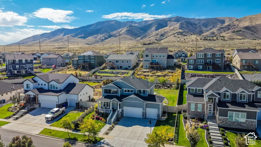 Aerial perspective of residential properties featuring multi-level construction, attached two-car garages, concrete driveways, and mountain backdrop