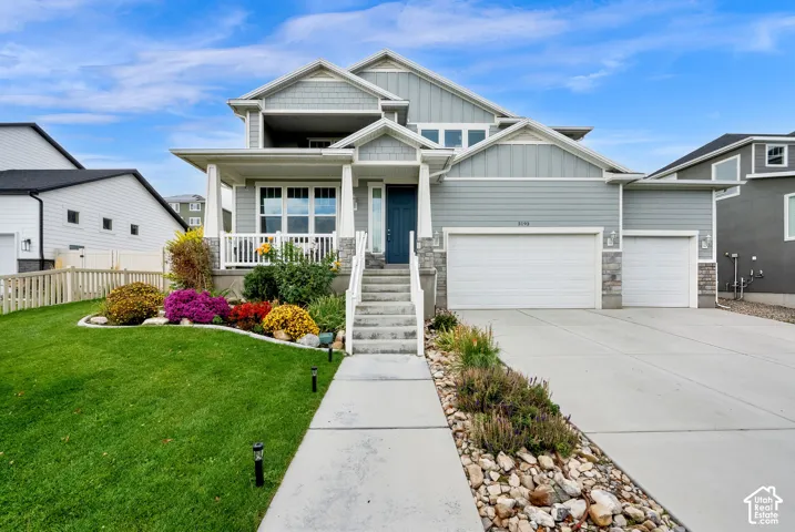 Two-story residence featuring composite siding, stone veneer accents, a covered front porch with white railing, and a three-car garage