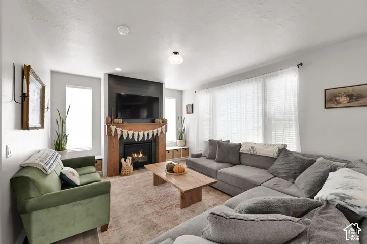 Living area featuring a floor-to-ceiling fireplace with wood mantle and dark wood-plank accent wall, built-in lower cabinetry, and large multi-panel windows