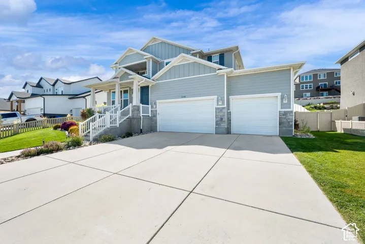 Multi-level exterior featuring horizontal and vertical siding, stone veneer accents, a covered front porch with white railing, and a three-car attached garage