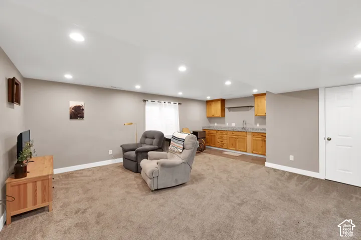 Open-concept space featuring recessed lighting, wall-to-wall carpeting, and a wet bar with natural wood cabinetry and stone-finish countertops