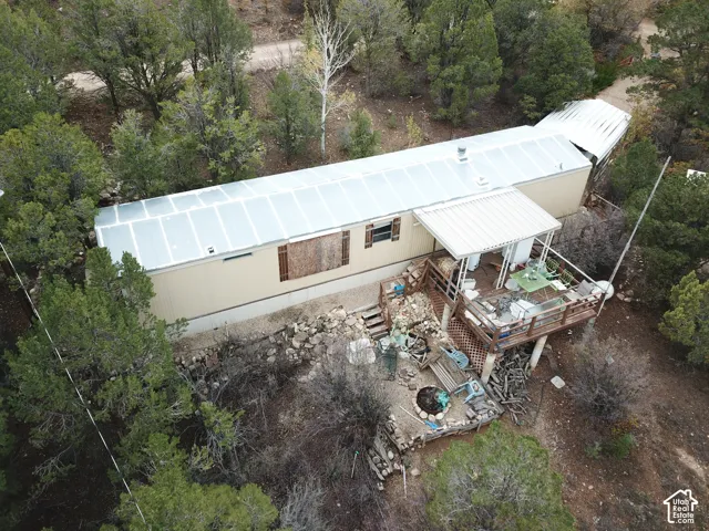 Exterior featuring a metal roof, elevated wooden deck with a covered portion, and a natural woodland setting