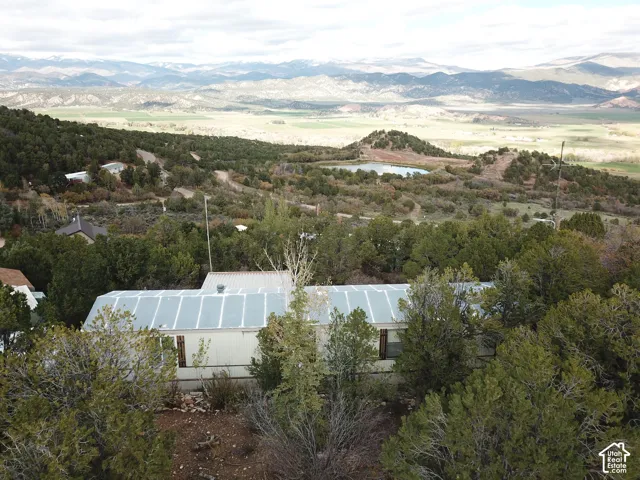 Aerial perspective featuring a metal roof, surrounding evergreen landscape, and mountainous horizon