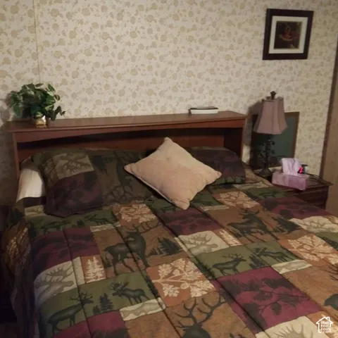 Built-in wood-finish headboard with integrated shelving and floral patterned wallcovering
