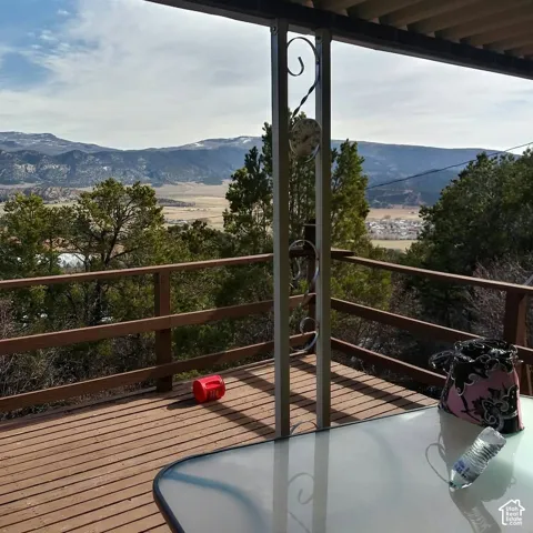Covered deck featuring wood-plank flooring, horizontal wooden railings, and mountain terrain backdrop