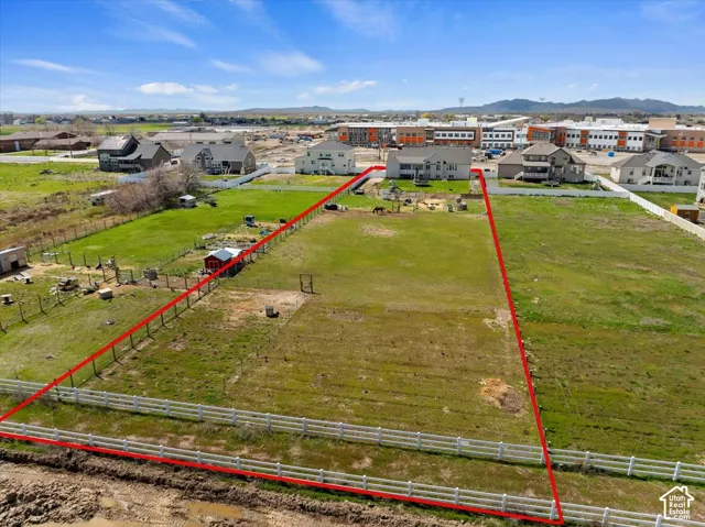Expansive lot featuring perimeter fencing, open grass areas, and mountain backdrop