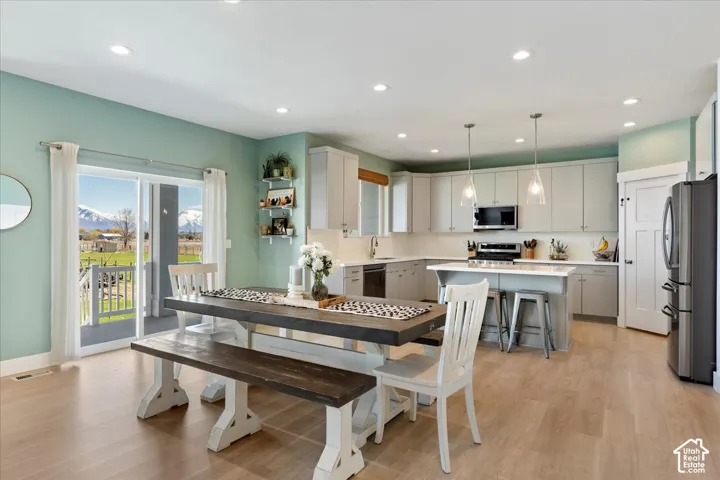 Kitchen featuring light gray cabinetry, a center island, recessed ceiling lighting, sliding glass doors, and wood-finish flooring