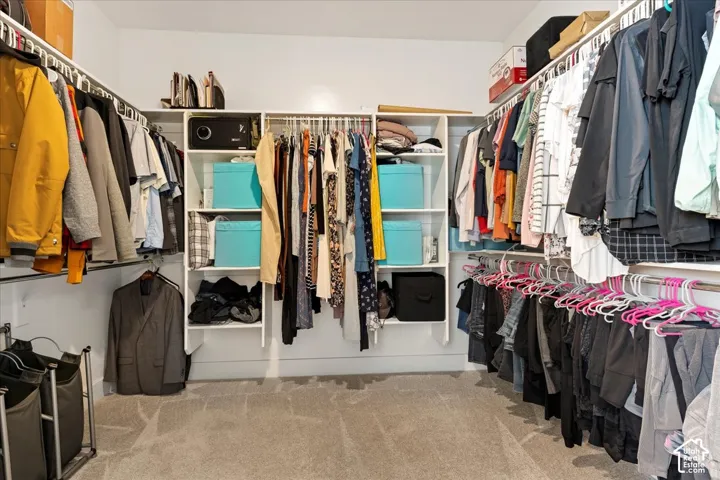 Walk-in closet featuring floor-to-ceiling white shelving units and multiple levels of integrated hanging rods