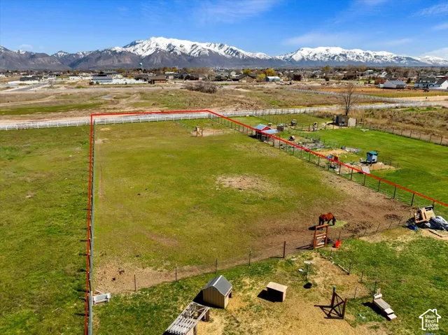 Expansive lot featuring perimeter fencing, a grass-covered pasture, and a snow-capped mountain backdrop