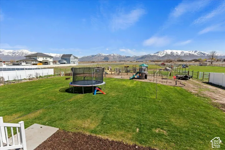 Expansive backyard featuring a fenced perimeter, manicured lawn, and mountainous horizon
