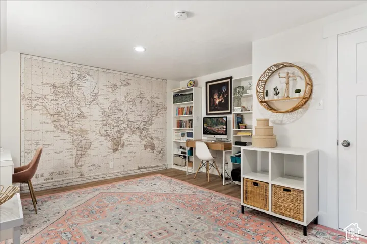 Room featuring wood-finish flooring, recessed lighting, and built-in white shelving