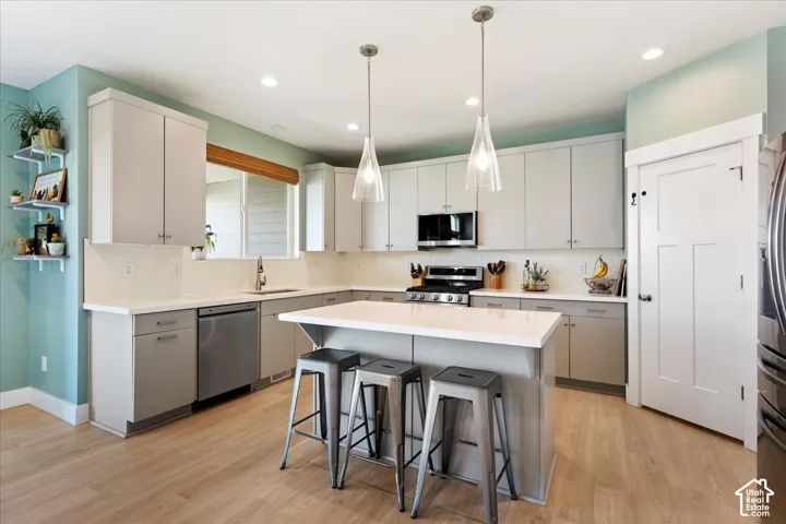 Kitchen featuring light-toned cabinetry, quartz countertops, a central island, recessed lighting, and wood-finish flooring