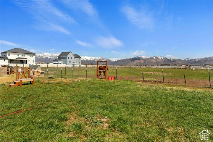 Expansive pasture featuring perimeter fencing, mountain backdrop, and natural grass grounds