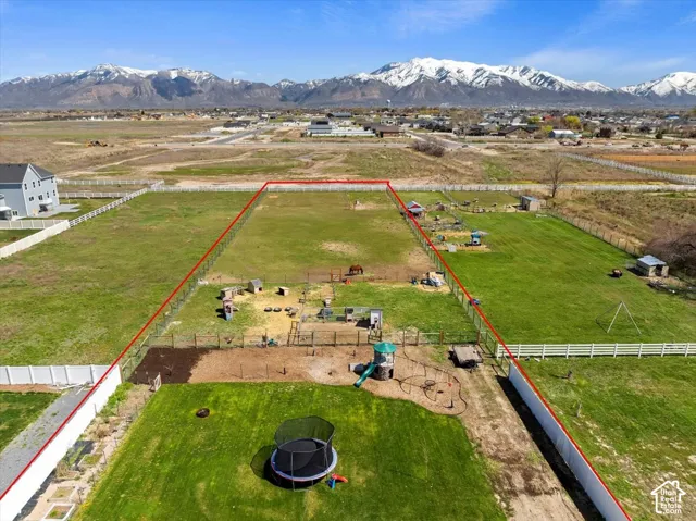 Expansive parcel of land featuring perimeter fencing, open pasture space, and snow-capped mountain backdrop