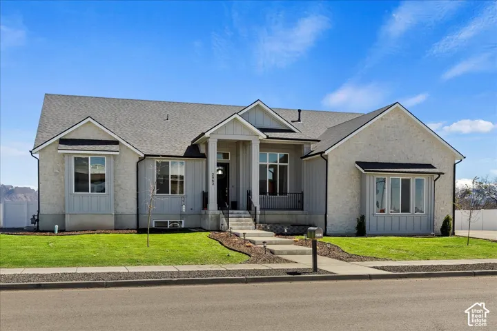 Single-story residence featuring a combination of stone masonry and vertical siding, a covered entry with metal railings, a peaked roofline, and multi-pane windows