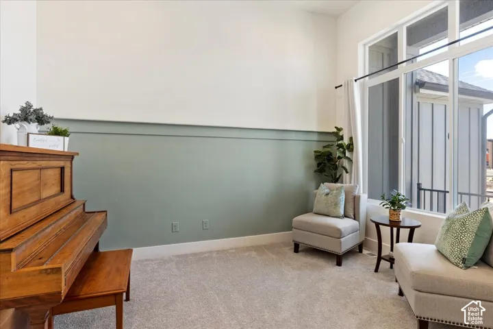 High ceilings featuring expansive windows with floor-to-ceiling glass, horizontal wall molding, and neutral carpeting
