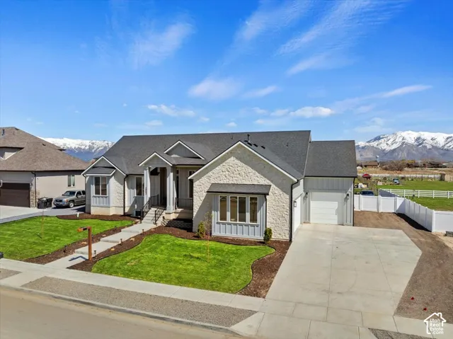 Exterior featuring a stone and board-and-batten facade, multi-gabled roofline, concrete driveway, and front landscaping