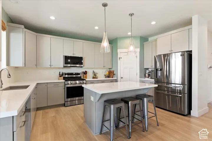 Kitchen featuring flat-panel cabinetry, quartz countertops, stainless steel appliances, a central island, and wood-finish flooring
