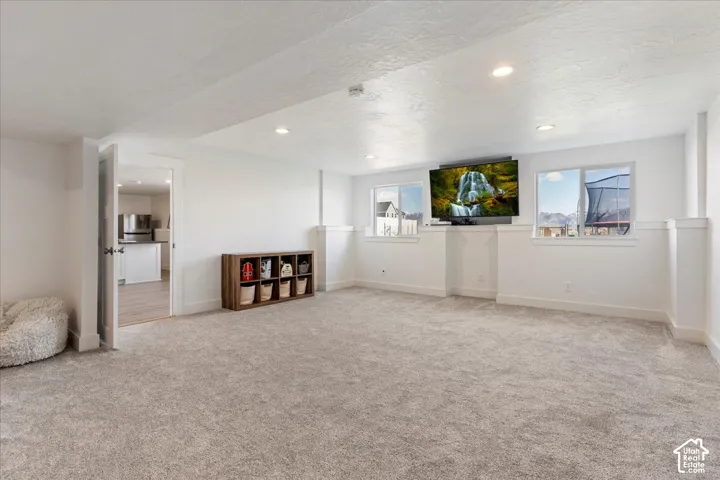 Open-concept room featuring neutral wall-to-wall carpeting, recessed ceiling lighting, and dual windows