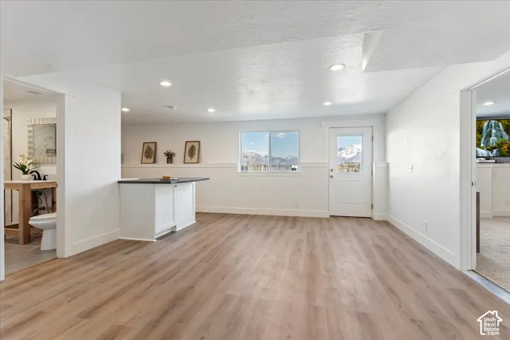 Open interior space featuring wood-finish flooring, recessed lighting, a built-in wet bar with dark countertop, and a glass-pane exterior door