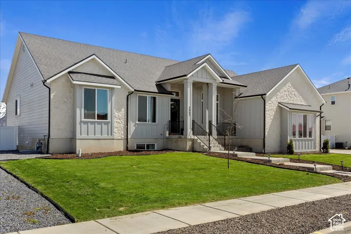 Exterior featuring a combination of stone and vertical siding, covered front porch with a gabled roofline, and a manicured lawn