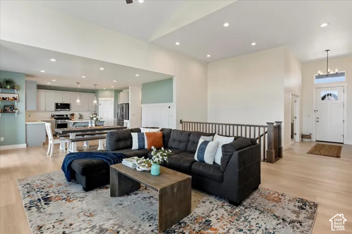 Open-concept floor plan featuring vaulted ceilings, recessed lighting, wood-finish flooring, and a staircase with stained wood railings