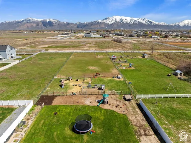 Expansive acreage featuring perimeter fencing, cross-fencing, manicured turf, and a prominent mountain range backdrop
