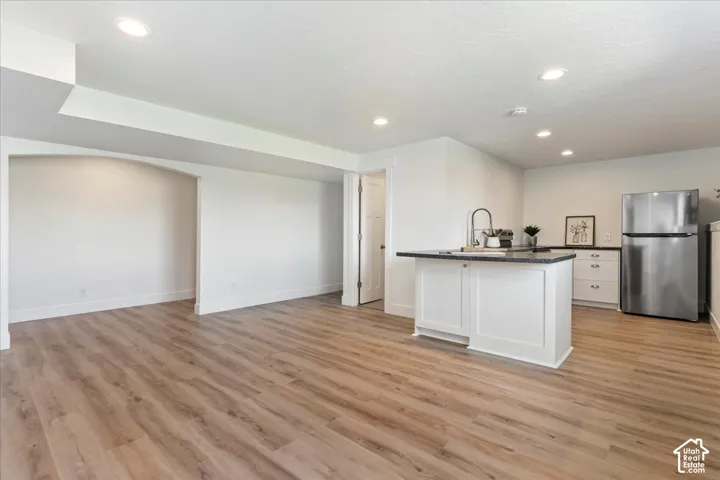 Open-concept space featuring wood-finish flooring, recessed lighting, and an arched architectural detail