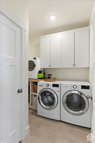 Laundry area featuring neutral tile flooring, white shaker-style cabinetry, and open lower shelving