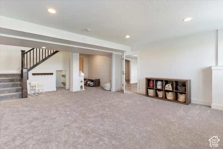 Open-concept interior featuring recessed lighting, wall-to-wall carpeting, and a staircase with a dark wood handrail