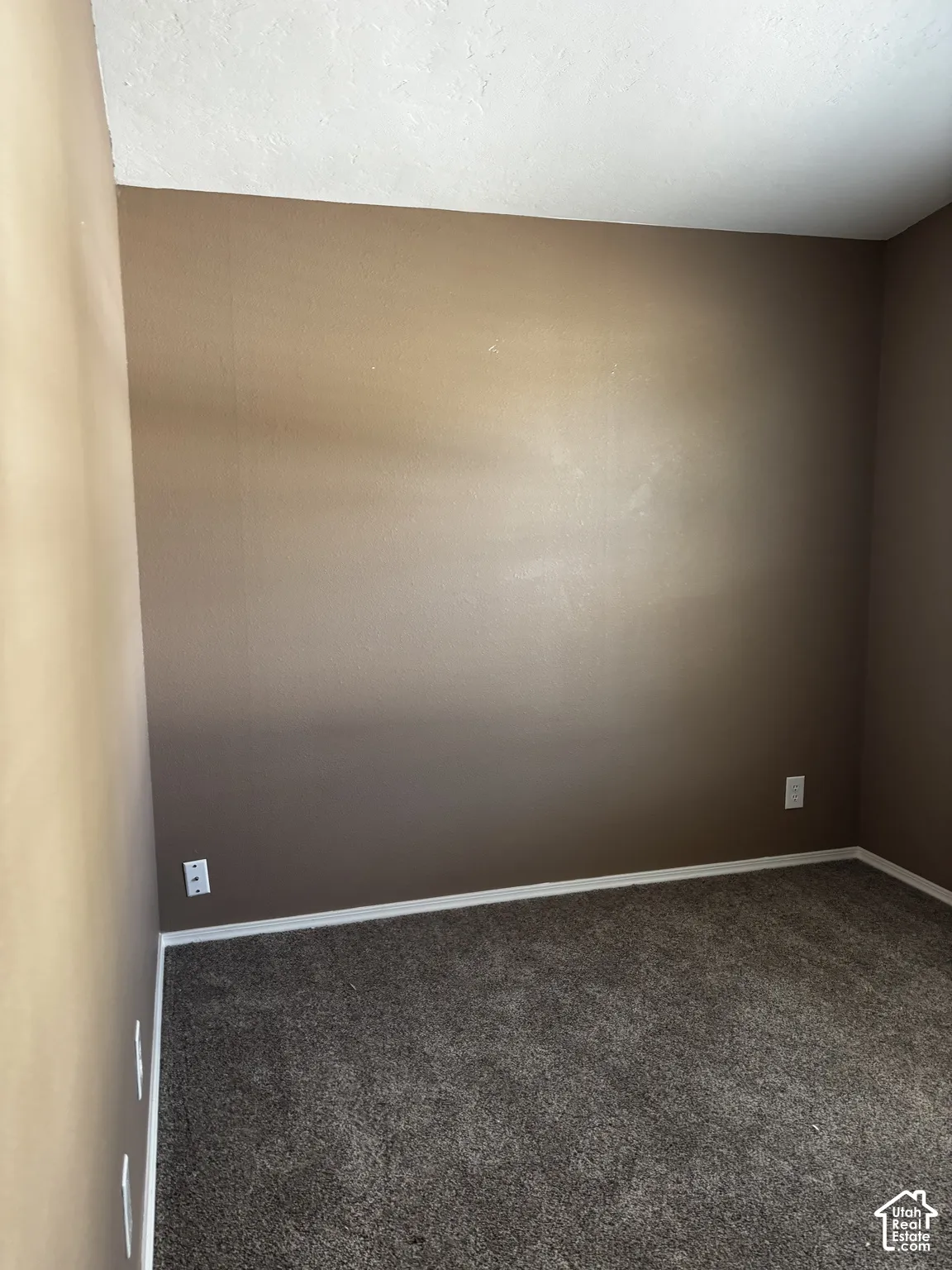 Neutral-toned wall finish with gray carpeting and integrated electrical outlets