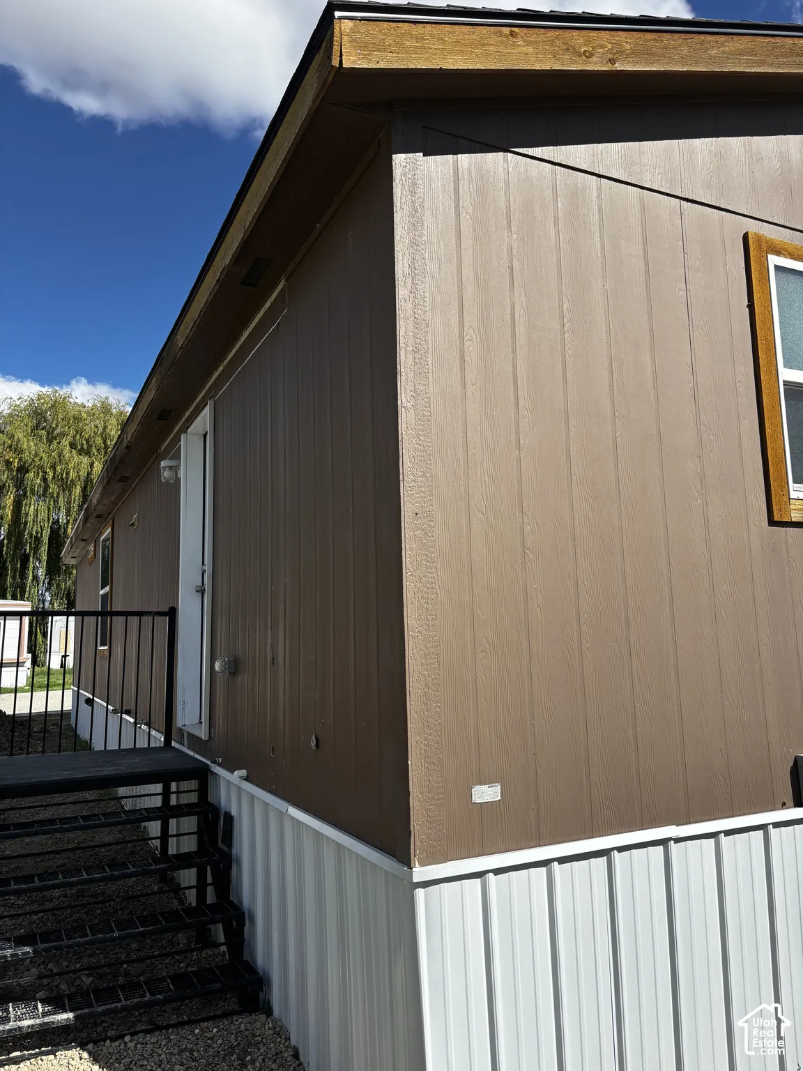 Exterior featuring vertical panel siding, a white metal foundation skirt, and an attached black metal staircase with handrails