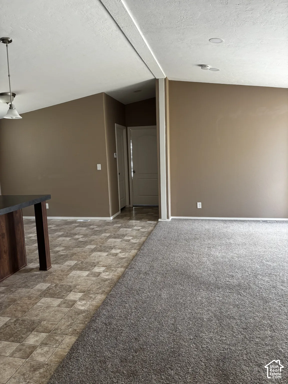 Vaulted ceilings with recessed lighting, multi-textured flooring featuring tile and carpet, and a built-in island structure