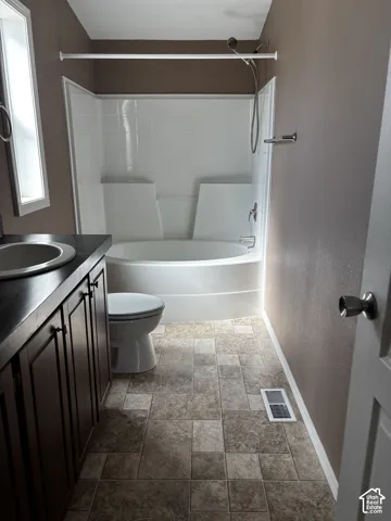 Bathroom featuring a white molded tub-shower combination, dark wood-finish cabinetry, a rectangular vanity sink, and textured tile flooring