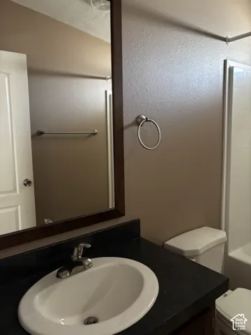Bathroom vanity featuring a dark solid-surface countertop, an integrated oval basin, a single-handle metal faucet, and a large rectangular mirror with a dark wood-finish frame