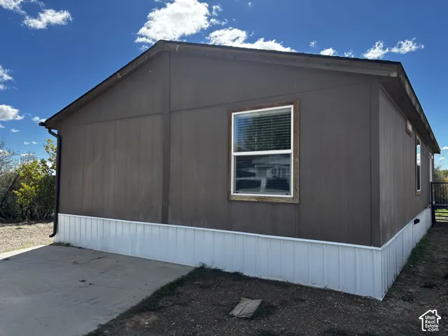 Exterior elevation featuring dark-toned vertical siding, white metal skirting, and a concrete pad