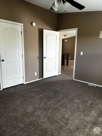 Neutral-toned interior featuring wall-to-wall carpeting, white two-panel interior doors with metallic hardware, and a ceiling fan with light fixture