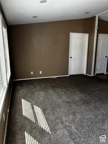 Room featuring neutral carpeting, recessed ceiling lighting, two white panel doors with black hardware, and large windows with blinds