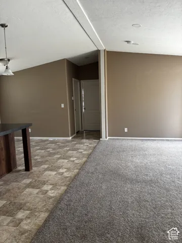 Vaulted ceilings with recessed lighting, multi-textured flooring featuring tile and carpet, and a built-in island structure