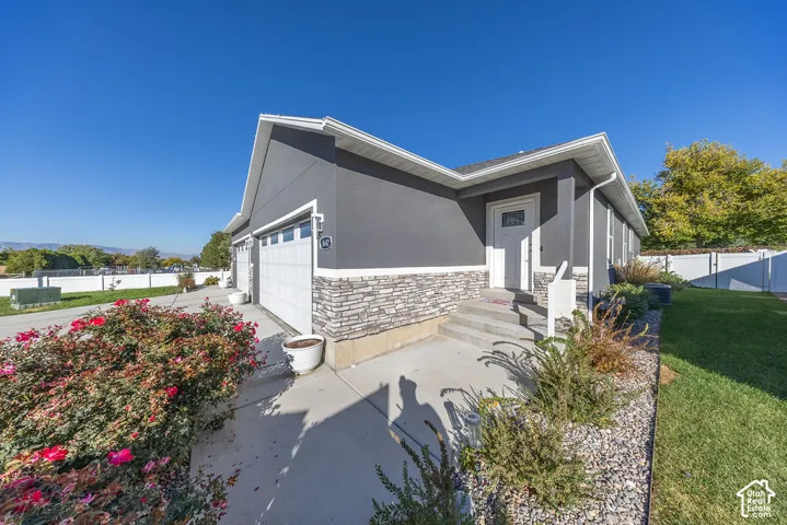 Exterior featuring stucco siding, stone veneer accents, an attached two-car garage, and concrete entryway steps