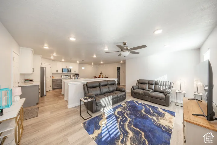 Open-concept interior featuring wood-finish flooring, recessed lighting, and a kitchen equipped with cabinetry, a built-in microwave, and a stainless steel refrigerator