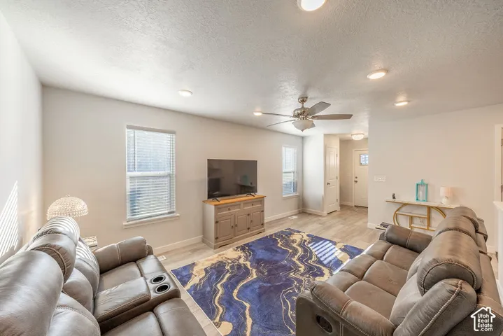 Living area featuring recessed lighting, a ceiling fan, wood-finish flooring, and multiple windows