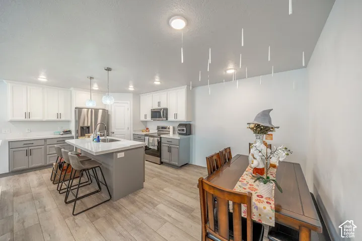Kitchen featuring a central island with a stone-finish countertop, dual-tone cabinetry, stainless steel appliances, and wood-finish flooring